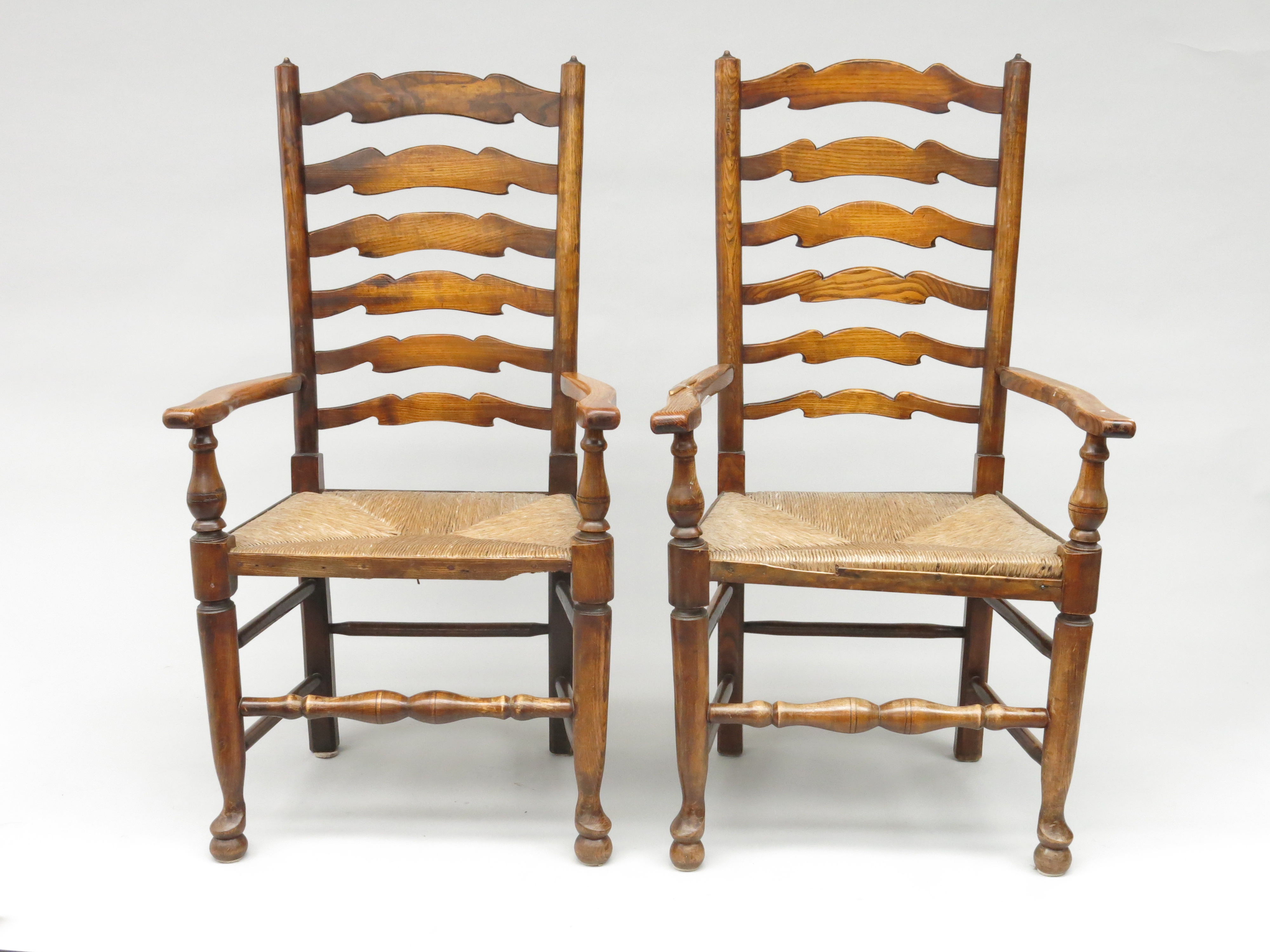 A pair of ladderback rush seated armchairs, early 20th century, height 111cm, width 63cm.