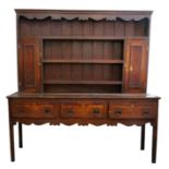 A George III oak and mahogany crossbanded dresser, the shaped apron above three shelves,