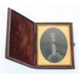 A Victorian ambrotype type oval photographic portrait of a seated young gentleman wearing an