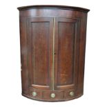 A George III oak bow front hanging corner cupboard, with mahogany crossbanding,