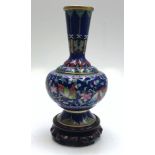A cloisonne vase, 20th century, decorated with flowers and butterflies on a wooden stand,
