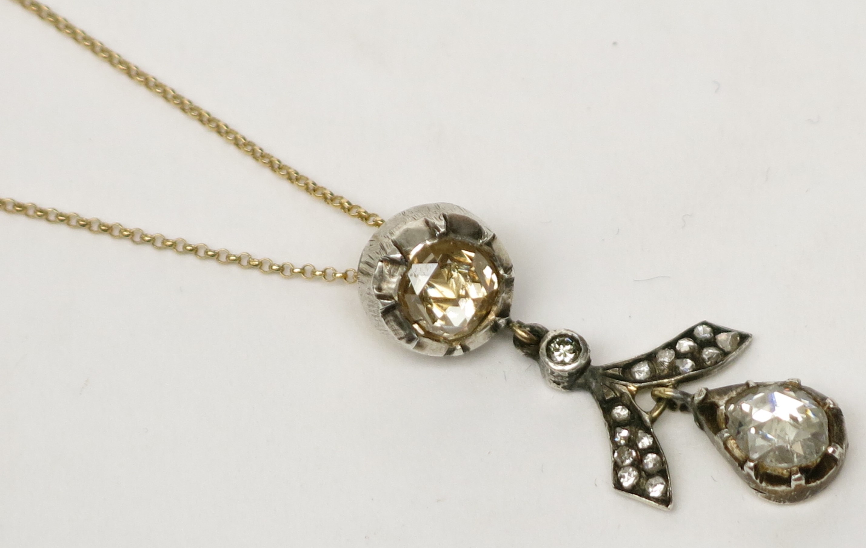 An impressive diamond pendant from a yellow old cut stone of approximately 1ct hangs a stylised