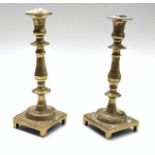 A pair of continental brass candlesticks, 18th century, with turned stems on stepped bases,
