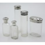 A set of four variously sized cut glass toilet bottles with silver tops together with one other