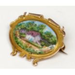 A pre-war gold enamel brooch by Spencer, London, it shows a cottage set amongst trees,