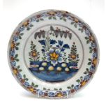 A Dutch Delft polychrome plate, 18th century, painted with flowers and a fern issuing from rockwork,