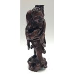 A Chinese carved hardwood figural lamp base of a buddha holding a fish, 19th century, height 48cm.