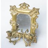 A brass small mirrored wall sconce, late 19th century, the rectangular frame with mask,