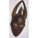 An African wooden Ibiobio tribal mask with horns, Nigeria, height 42cm width 15.5cm.