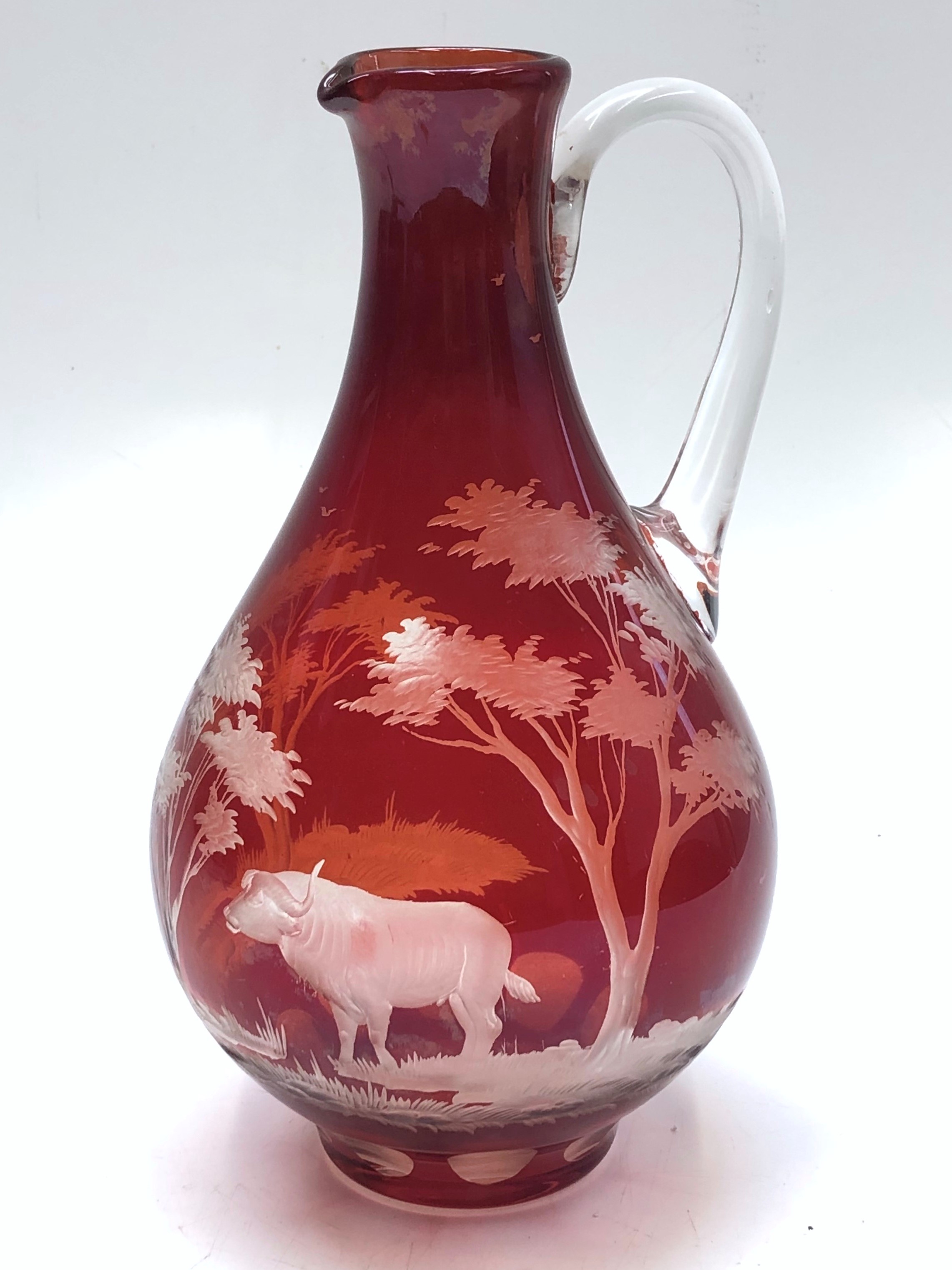 A ruby overlay jug, 20th century, engraved with a buffalo in an African landscape, height 27cm.