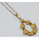 An Arts and Crafts high purity gold pendant worked with a border of grapes and vine leaves.