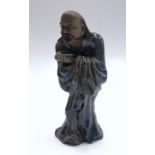 A Chinese blue glazed pottery figure of a man holding a begging bowl, height 25cm.