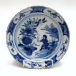 A Dutch Delft blue and white plate, 18th century, painted with a figure in an oriental garden,