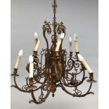 An ornate gilt brass multi branch chandelier with cast masks and scrolls.