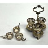 A three section EPNS egg cruet and a set of three pierced engraved silver coloured metal salts.