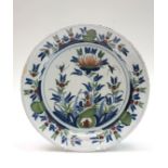 An English Delft charger, 18th century, decorated red, blue and green flowers and insects,