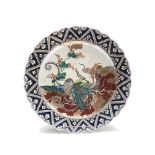 A large Japanese porcelain charger, 19th century, with a stylised bird, leafy vines and clouds,