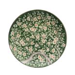 A Japanese porcelain charger, Meiji period, the green ground with flowering trees, diameter 37cm.