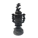 A Japanese bronze urn, cover and stand, Meiji Period, the cover cast with a flowering shrub,