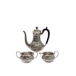 An Indian silver coffee pot with matching milk jug and sugar bowl each repousse decorated and