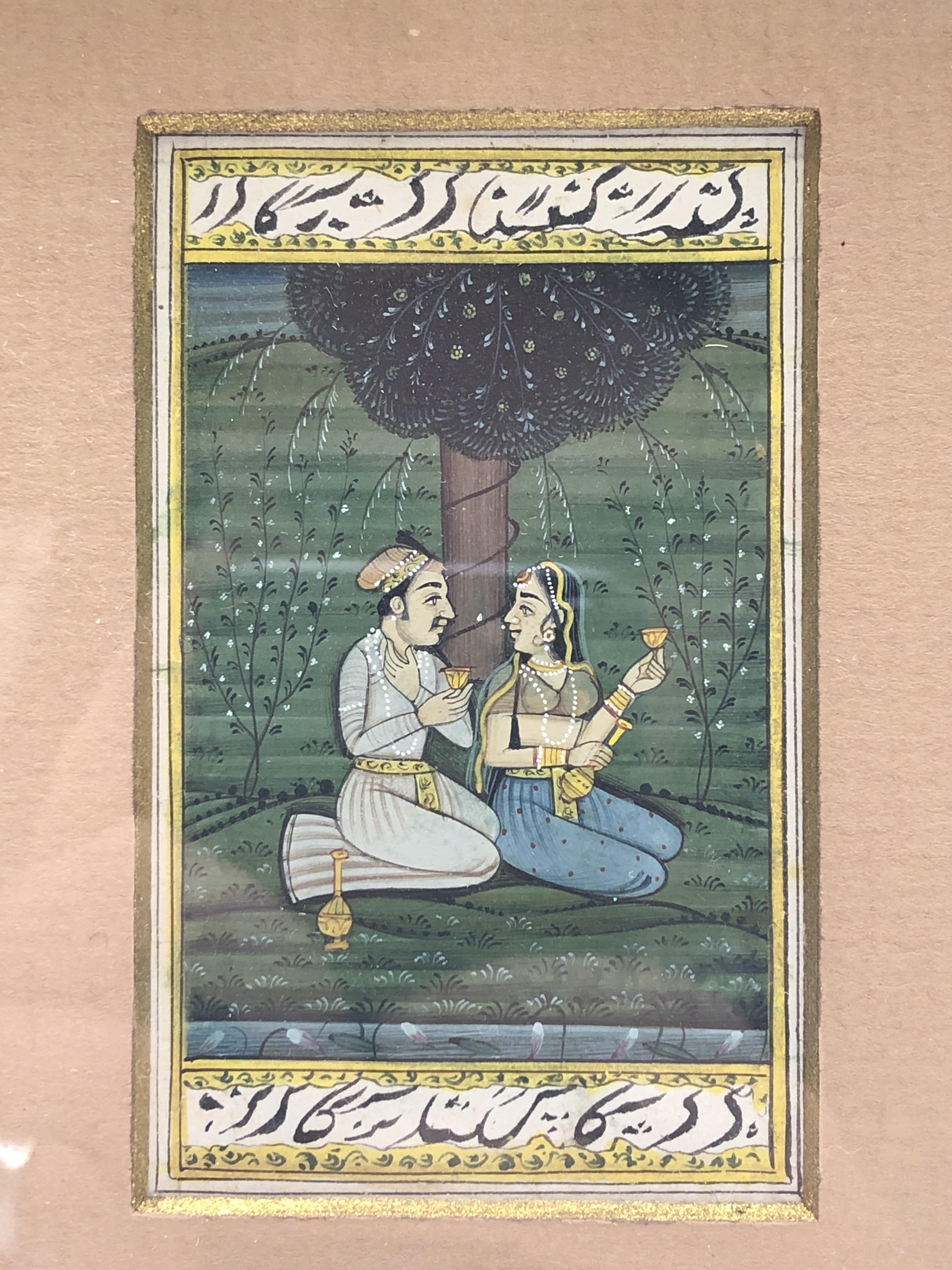 A miniature Indian painting, of a couple seated beneath a tree, calligraphy to borders, 8 x 5cm. - Image 2 of 3