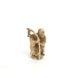 A Chinese carved ivory netsuke, an elderly gentleman carrying a bamboo cane with fish,