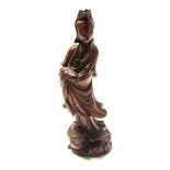 A Chinese carved wood figure of Guanyin, circa 1900, standing upon a lily pad and a stylised dragon,