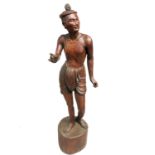 A large Burmese carved wood statue of a semi naked man, standing on a plinth, height 158cm,