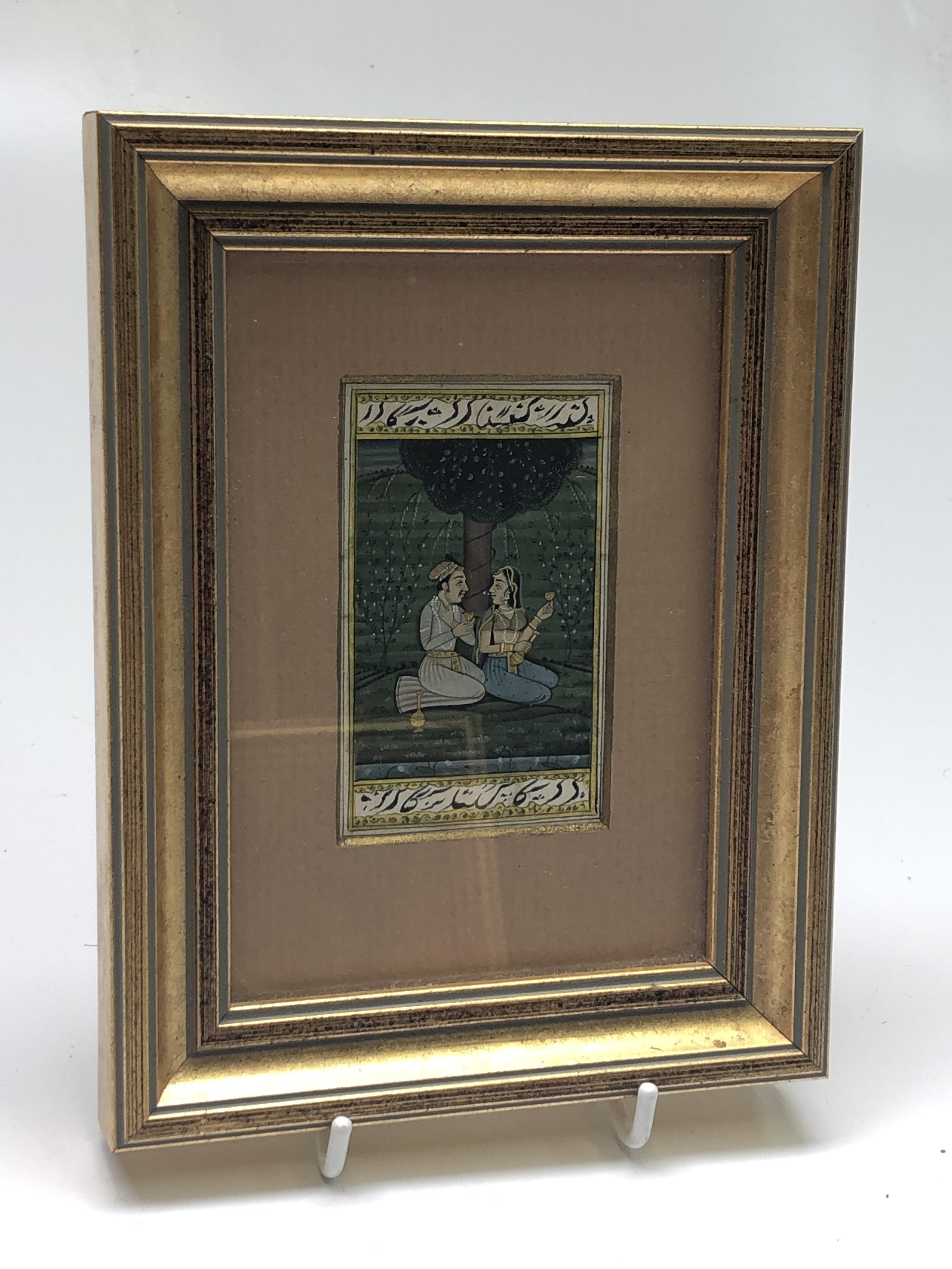 A miniature Indian painting, of a couple seated beneath a tree, calligraphy to borders, 8 x 5cm.
