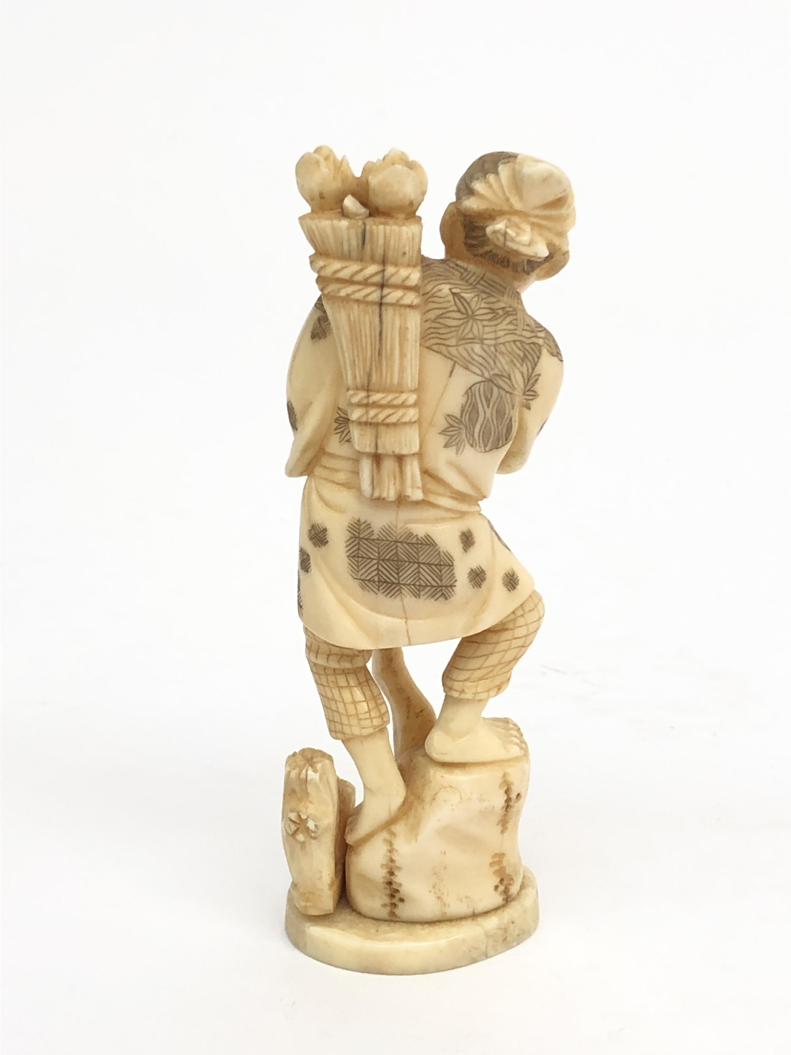 A Japanese ivory okimono of a farmer, circa 1900, with a bundle of flowers over his shoulder, - Image 2 of 3