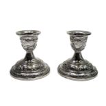 A pair of Indian silver low candlesticks, repousee decorated with village scenes,