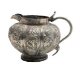 A Chinese silver jug, 19th century, the fluted body decorated with trees, pagodas,