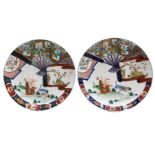A pair of Japanese Imari porcelain large plates, each painted with a figure reading a scroll,