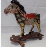 An early 20th century composition pull-a-long or sit-on pony on a wood base with two metal and two