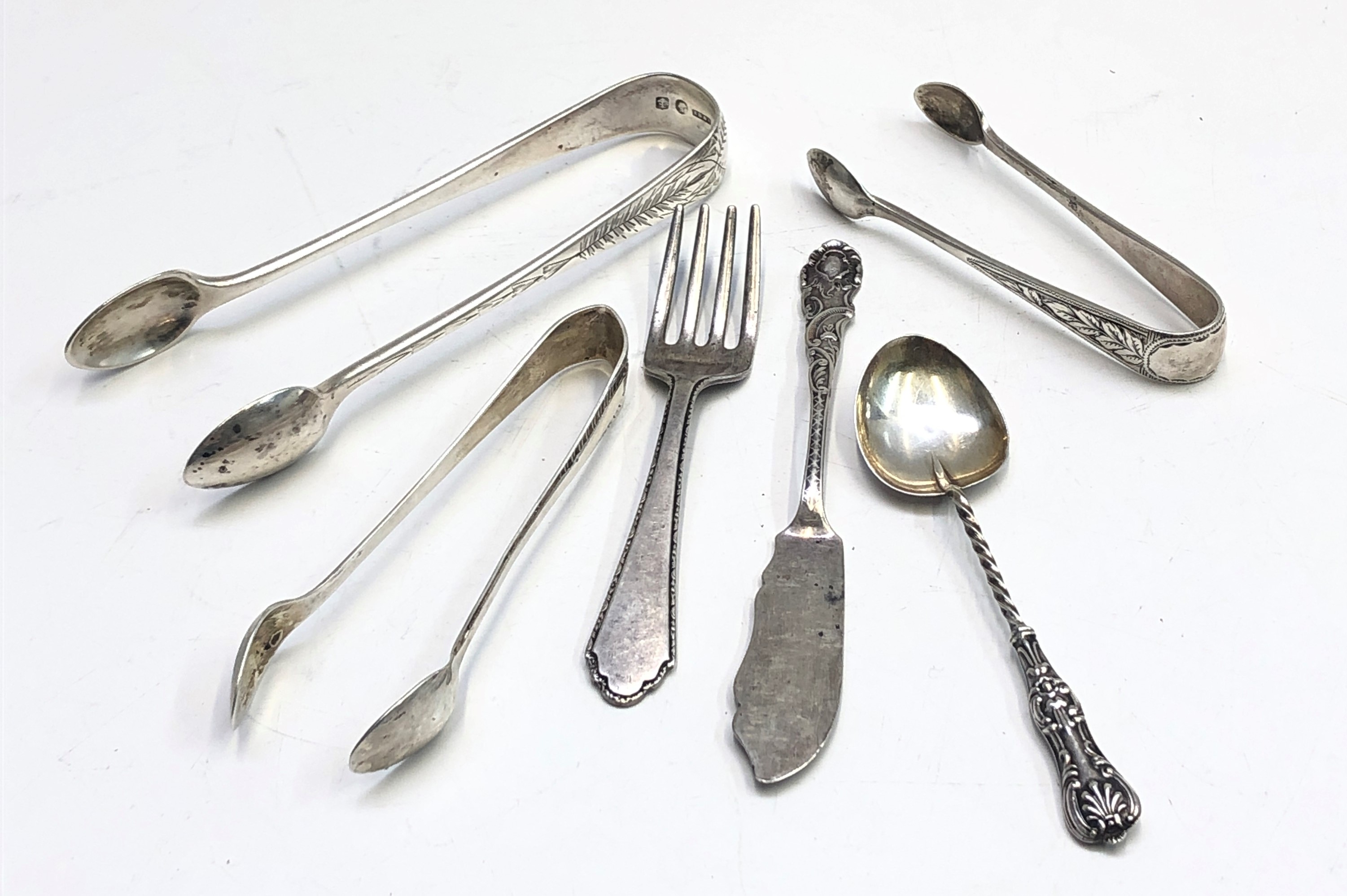 Three pairs of silver sugar tongs together with three other pieces of silver cutlery, 3.3oz.