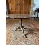A George III oak tripod table, the circular snap top on a turned baluster stem, and downswept