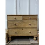 A small pine chest of drawers with wooden knobs.