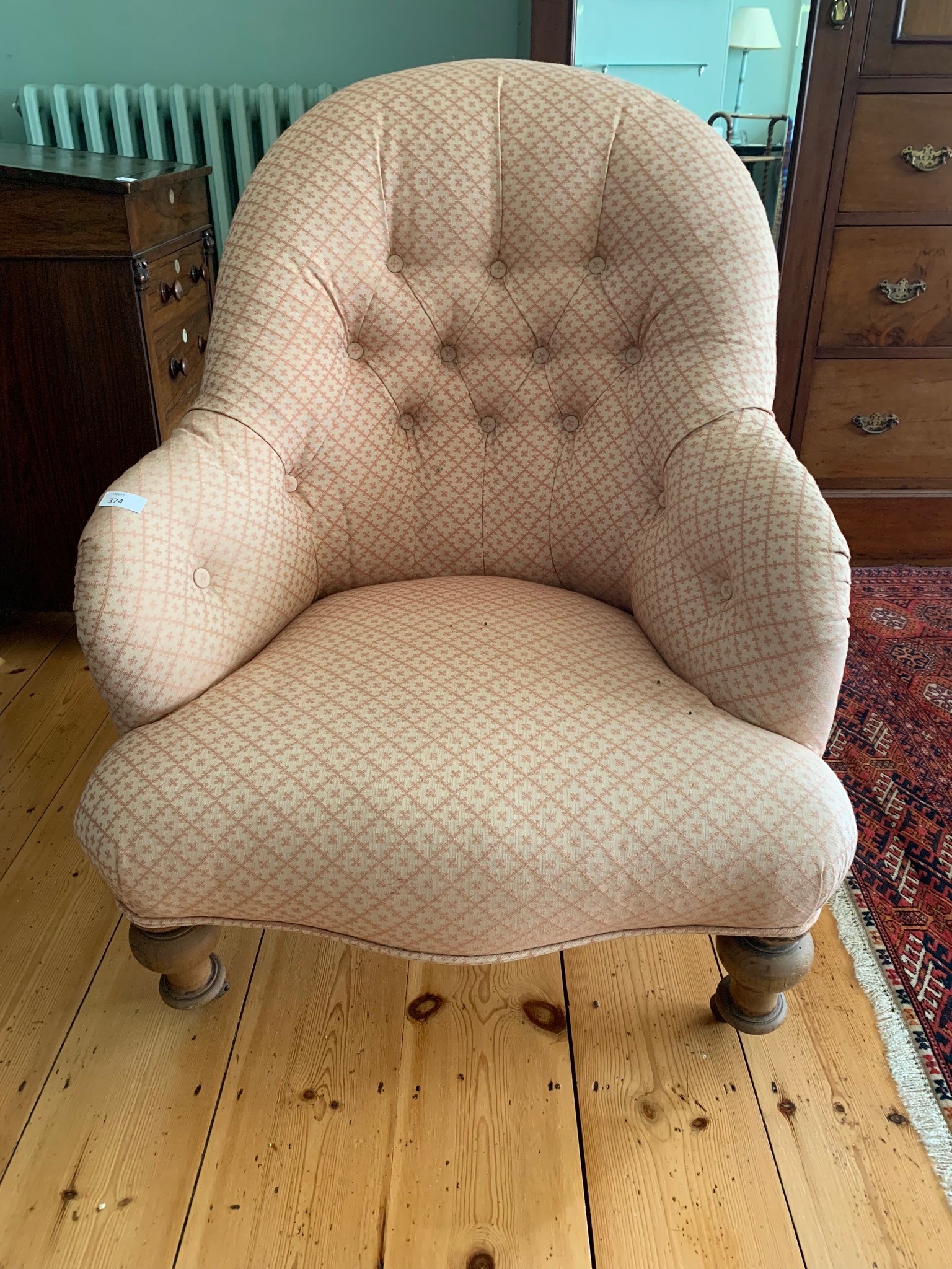 A Victorian tub armchair, with a padded back, arms and seat, on turned tapering legs. (Dimensions: