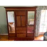 An Edwardian mahogany wardrobe, the central panelled door enclosing fitted shelves, above three