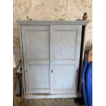 A painted pine cupboard with sliding doors.