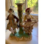 An early 19th century porcelain candelabra, the nozzle between two dancing figures in 18th century