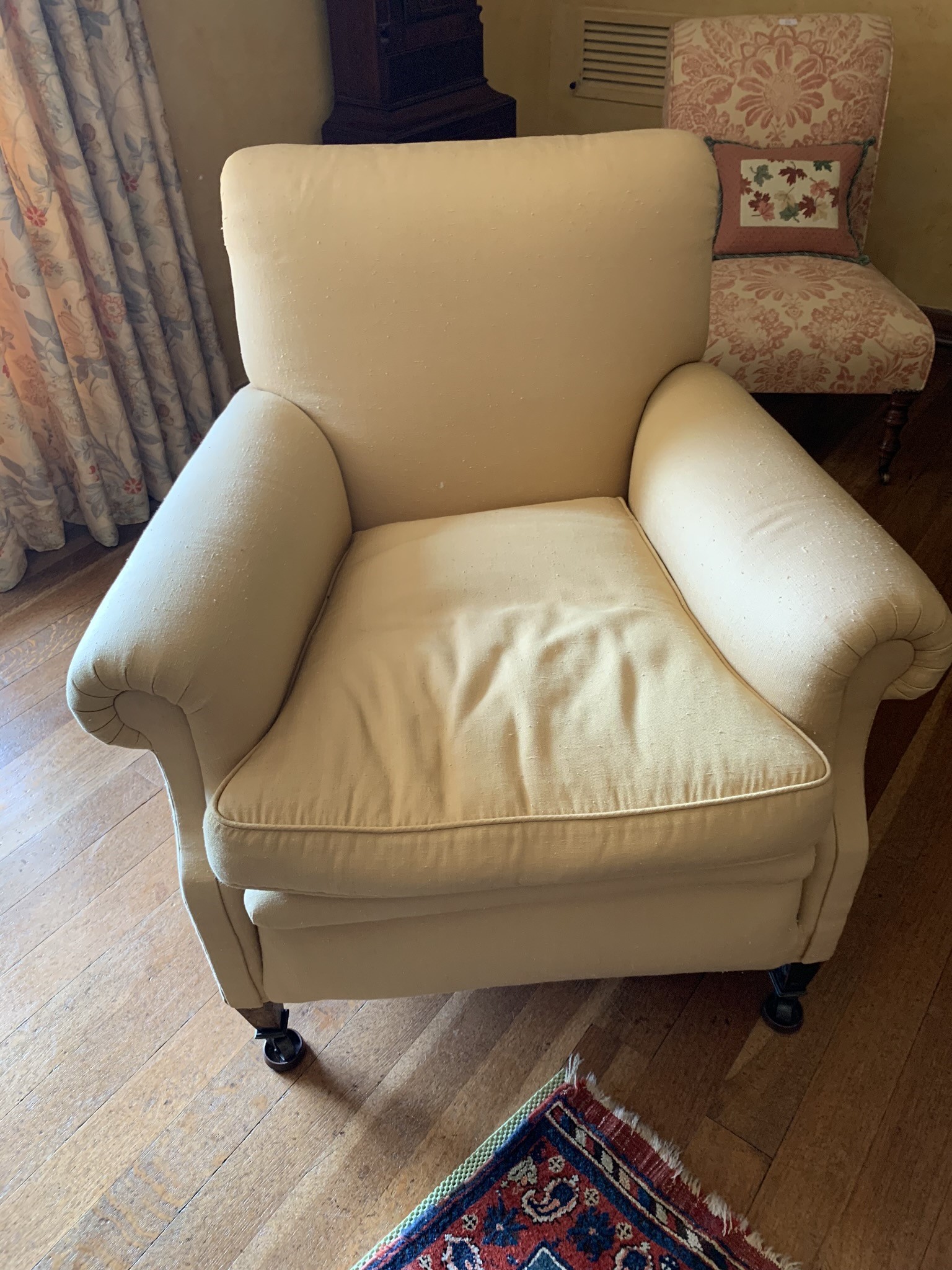 An upholstered armchair, late 19th century, with padded back, arms and seat, on square tapering