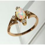 A gold ring with a central oval opal within diamonds at the cardinal points.