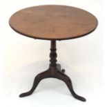 A George III mahogany tilt top tripod table, the circular top on a turned baluster stem and