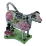 An early 19th Century Yorkshire pottery cow creamer with milk maid, the cow's body sponge