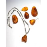 An amber pendant necklace and five other pieces of amber, largest length 6.7cm.