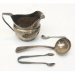 A silver helmet cream jug with reeded rim and base, a silver ladle 6.9oz and a pair of silver