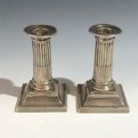 A pair of Edwardian Walker & Hall filled silver Doric column candlesticks with beaded rim and