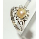 An 18ct. white gold ring with a flower-head cluster of a 7.2mm pearl within ten diamonds.