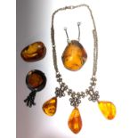 An amber necklace, an amber brooch and two pieces of amber, largest 5.5 x 4.6cm.